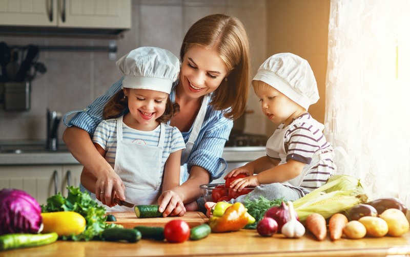 Frau kocht mit Kindern ein gesundes Essen
